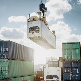 Mehrere Transport-Container und ein Kran, der gerade einen Container transportiert