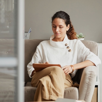 Eine Frau sitzt auf der Couch mit ihrem Tablet