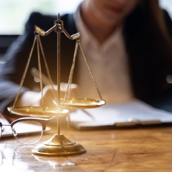 Dekorative goldene Waage auf einem Tisch mit einer Person im Hintergrund, die Notizen macht