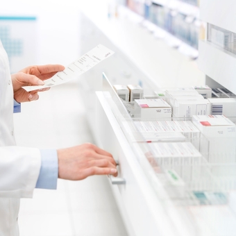 Pharmazeut öffnet Apothekenschrank mit Medikamenten