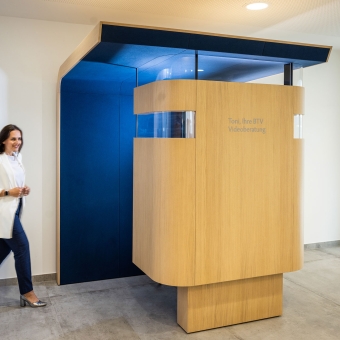 Eine Frau bewegt sich auf ein Separee für die Videoberatung zu