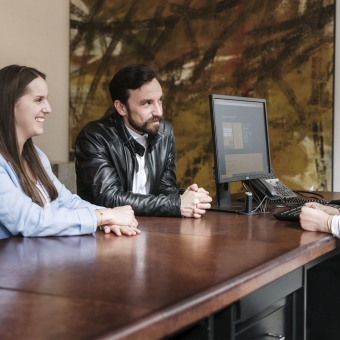 Zwei Personen lachen und unterhalten sich mit einer Bankmitarbeiterin.
