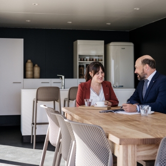 Zwei Personen unterhalten sich an einem Esstisch.