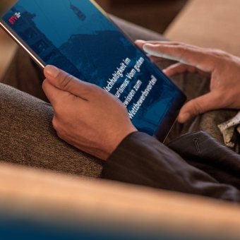 Hände halten ein Tablet in der Hand., auf dem zu lesen ist: Nachhaltigkeit im Tourismus: Vom guten Gewissen zum Wettbewerbsvorteil.